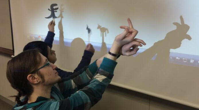 Rhys and a young girl with long curly hair sitting at a table, leaning together and smiling.